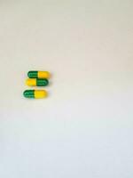 geïsoleerd wit foto van drie geneeskunde capsules groen en geel.
