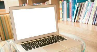 laptop met blanco scherm Aan houten tafel in voorkant van bibliotheek - technologie concept foto