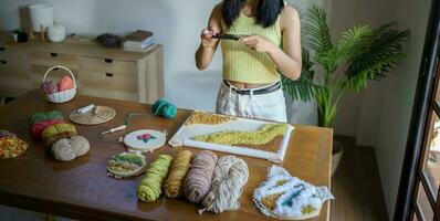 stempel naald. Aziatisch vrouw maken handgemaakt hobby breiwerk in studio werkplaats. ontwerper werkplaats handgemaakt ambacht project diy borduurwerk concept. foto