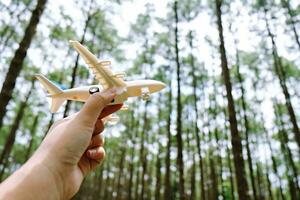 dromen van reis. hand- Holding vliegtuig speelgoed- model. vlak nemen vlucht en uittrekken foto