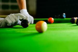 man's hand- en keu arm spelen snooker spel of voorbereidingen treffen het richten naar schieten zwembad ballen Aan een groen biljart tafel. kleurrijk snooker ballen Aan groen fries. foto