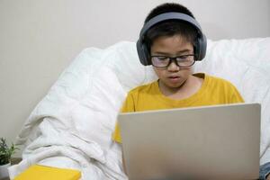 jong jongen gebruik makend van computer en mobiel apparaat aan het studeren online. foto