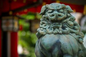 Japans standbeeld van een shishi in de kant van een Shintoïsme tempel met een mooi hoor bokeh in de achtergrond foto