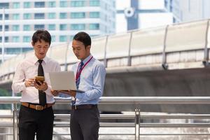 twee zakenlieden werken aan stoep met smartphone en notebook voor bedrijfsconcept.