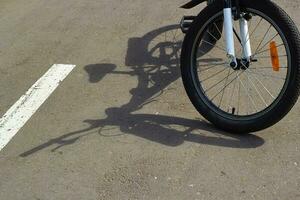 fiets schaduw Aan grijs asfalt. zonnig dag wiel foto