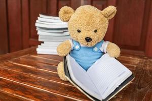 de teddybeer zit een boek te lezen en concepten te lezen foto