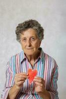 oud vrouw houdt een hart in haar handen foto
