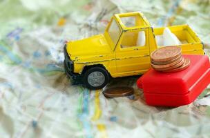 klein geel auto, koffer en euro munten Aan een kaart foto