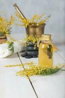 mimosa bloemen massage olie in glas fles. foto