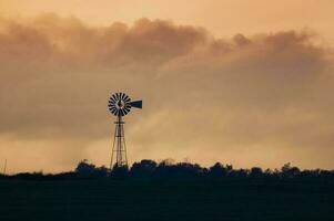 windmolen in platteland Bij zonsondergang, pampa, patagonië, argentinië. foto