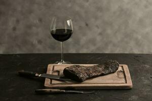 geroosterd rundvlees ribben met een glas van rood wijn gepresenteerd Aan de tafel, traditioneel Argentijns keuken, asado barbecue, Patagonië, Argentinië. foto