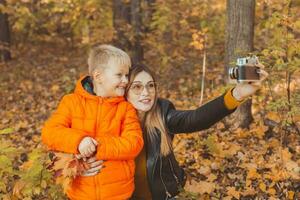 zoon en moeder zijn nemen selfie Aan camera in herfst park. single ouder, vrije tijd en vallen seizoen concept. foto