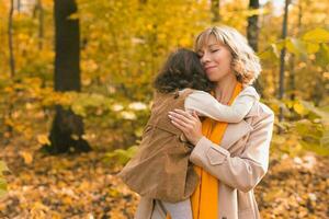 moeder met kind in haar armen tegen achtergrond van herfst natuur. familie en seizoen concept. foto