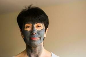 cosmetologie, spa, huid zorg en mensen concept - vrouw toepassen gelaats klei masker. schoonheid behandelingen. foto