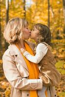 moeder en weinig dochter genieten van mooi hoor herfst dag in een park. seizoen, familie en kinderen concept. foto