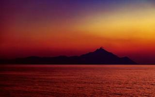 heilige berg athos bij zonsondergang. uitzicht vanaf het strand van platania, in de buurt van sarti, sithonia, schiereiland halkidiki, griekenland. foto