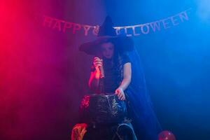 kind meisje heks voorbereidingen treffen een toverdrank in de ketel Bij halloween vakantie. foto