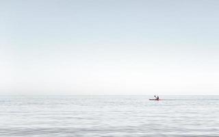 man kajakken op het zeer kalme water van de zee. man kajakken in de vroege namiddag op de egeïsche zee, griekenland. foto