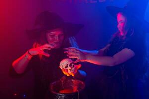 twee halloween heksen maken een toverdrank en toveren in halloween nacht. magie, vakantie en mysticus concept. foto