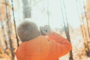 jongen met retro camera nemen afbeeldingen buitenshuis in herfst natuur. vrije tijd en fotografen concept foto