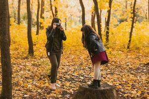 moeder nemen afbeelding haar charismatisch dochter Aan retro camera in herfst park. hobby's en vrije tijd concept. foto