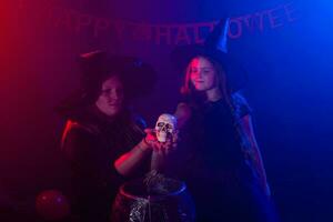 twee halloween heksen maken een toverdrank en toveren in halloween nacht. magie, vakantie en mysticus concept. foto