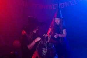 twee halloween heksen maken een toverdrank en toveren in halloween nacht. magie, vakantie en mysticus concept. foto