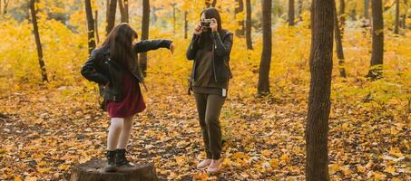 banier moeder nemen afbeelding haar charismatisch dochter Aan retro camera in herfst park. hobby's en vrije tijd concept. foto