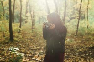kind meisje gebruik makend van een oubollig camera in herfst natuur. fotograaf, vallen seizoen en vrije tijd concept. foto