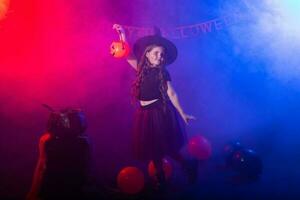grappig kind meisje in heks kostuum voor halloween met pompoen krik. foto