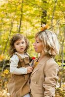 jong moeder met haar weinig dochter in een herfst park. vallen seizoen, ouderschap en kinderen concept. foto