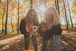 drie generaties van Dames en hond voelen pret kijken Bij camera poseren voor zelfportret afbeelding samen, grappig opgewonden kind, mam en grootmoeder hebben pret genieten weekend nemen selfie Aan apparaatje in herfst foto