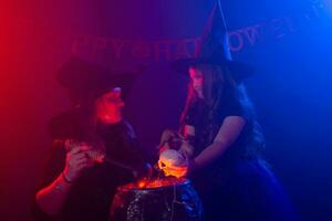 twee halloween heksen maken een toverdrank en toveren in halloween nacht. magie, vakantie en mysticus concept. foto