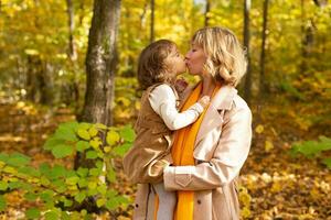 moeder en weinig dochter genieten van mooi hoor herfst dag in een park. seizoen, familie en kinderen concept. foto