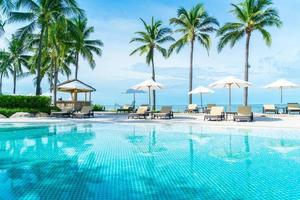 prachtig tropisch strand en zee met parasol en stoel rond zwembad in hotelresort foto