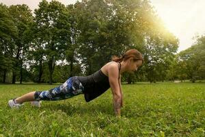 sport vrouw aan het doen geschiktheid Duwen omhoog in park foto