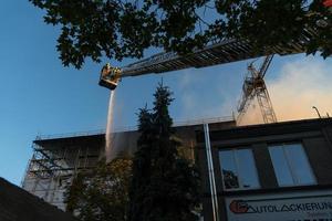 brandweerlieden klimmen ladder tegen gebouw en blussen een brand
