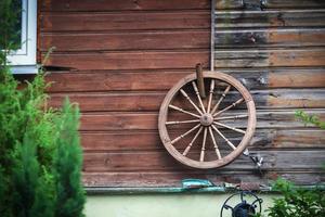 groot oud houten wiel dat aan de houten plankmuur van een landelijk huis hangt foto