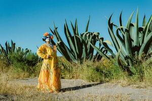 Mexicaans vrouw in kleurrijk jurk en schedel bedenken in de Mexicaans woestijn cactus foto