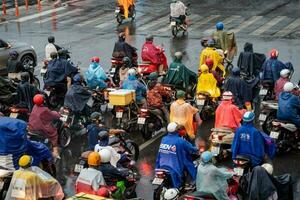 ho chi min, viet naam - 24 april 2023 Vietnamees mensen slijtage helm en regenjas rijden motor in zwaar regen en verkeer jam. foto
