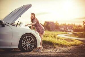 vrouw door de Open kap van een gebroken auto. foto