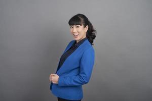 Glimlachende zakenvrouw in blauwe blazer op grijze achtergrond foto
