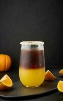 bevroren koffie met oranje sap in een transparant glas, verfrissend stuntelen koffie Aan de tafel foto