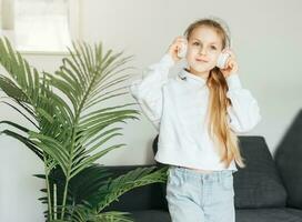 schattig weinig meisje luisteren naar muziek- in hoofdtelefoons foto