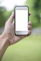 close-up man hand met smartphone in groen park, mockup van leeg scherm van smartphone of foto