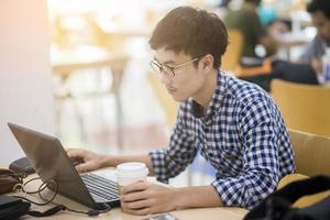 universiteitsstudent werkt met zijn laptopcomputer in bibliotheek foto