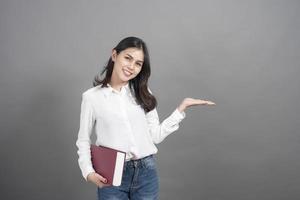 portret van vrouw universiteitsstudent met boek in studio grijze achtergrond foto