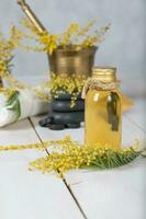 mimosa bloemen massage olie in glas fles. foto