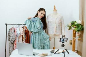 mooi Azië vrouw leven streaming verkoop kleren online met smartphone Bij haar winkel. klein bedrijf baasje, online markt concept. foto