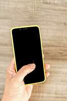 top visie mockup beeld van een handen Holding mobiel telefoon met blanco zwart scherm. foto